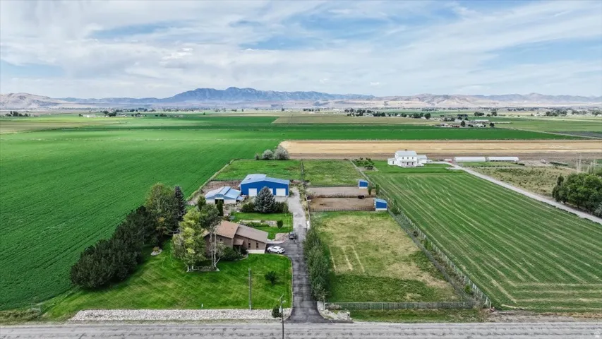 Expansive rural property featuring multiple structures, verdant fields, and a prominent mountain range backdrop