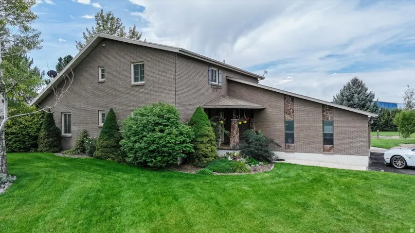 Brick exterior with stone accents, covered entry, gabled roofline, and established landscaping
