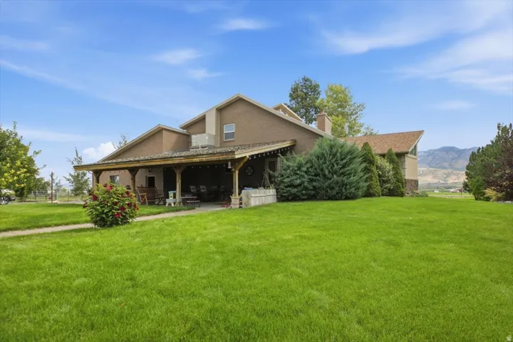 Expansive green lawn, covered porch with exposed wood beams, brown siding, and pitched rooflines