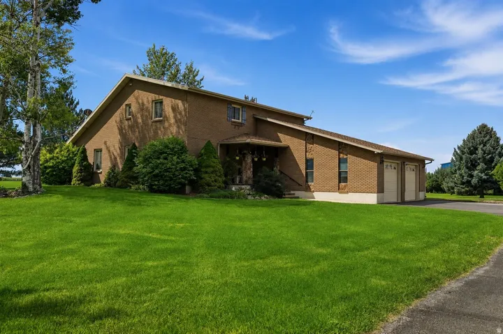Brick exterior with a peaked roofline, attached two-car garage, and established landscaping