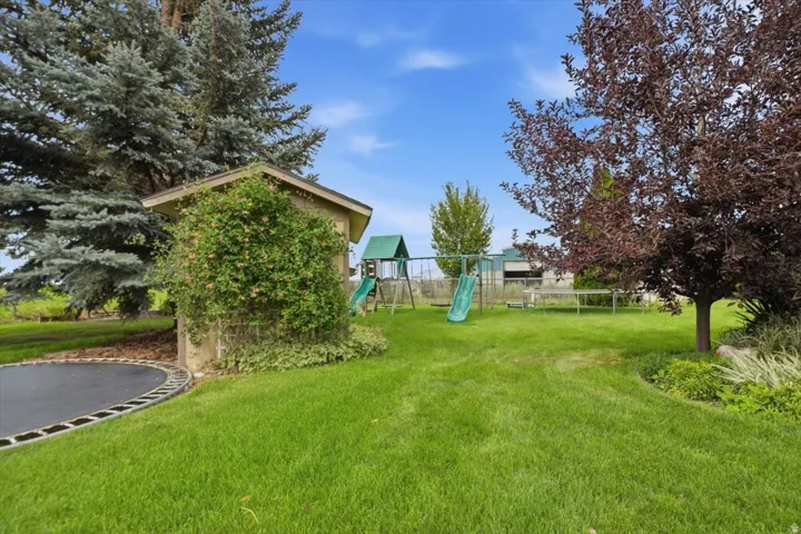 Expansive green lawn with mature trees and a built-in stone structure
