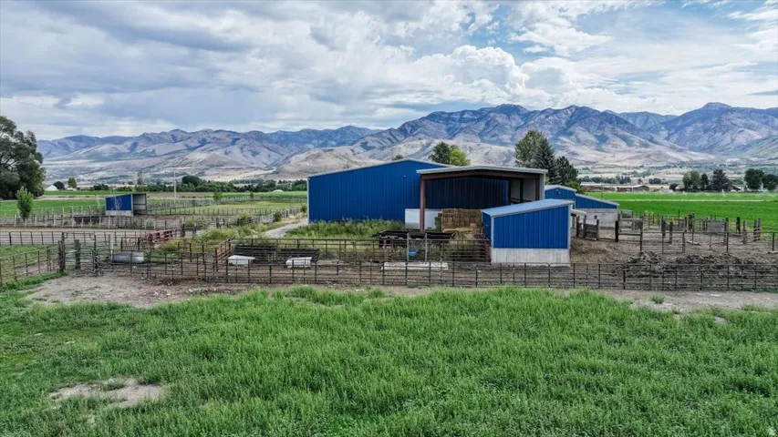 Multiple outbuildings with blue metal siding, open-sided structure, and surrounding fencing