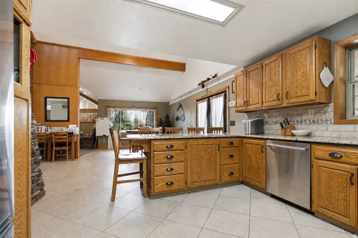 Kitchen featuring wood-finish cabinetry, stainless steel dishwasher, and granite-style countertops