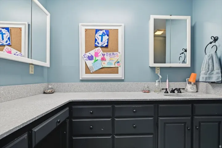 L-shaped countertop with integrated sink, dark wood cabinetry, wall-mounted medicine cabinet, and framed wall mirror