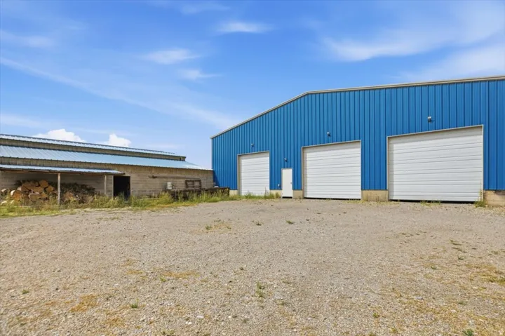 Blue corrugated metal building with three white roll-up doors and an entry door