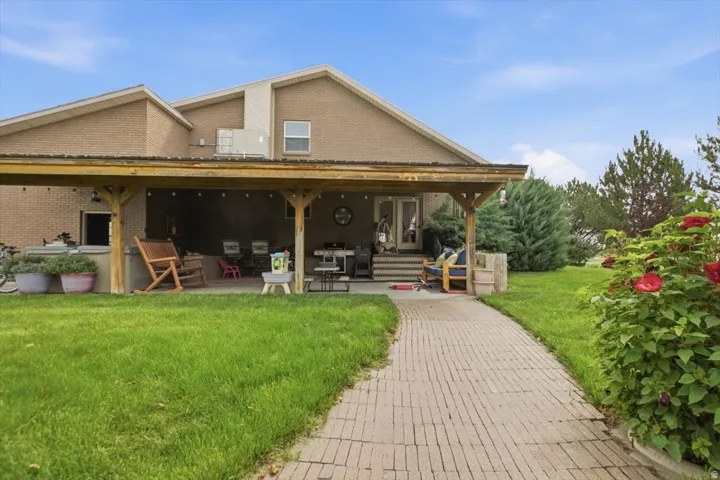 Brick home with an expansive covered porch featuring wooden beam construction and multiple seating areas