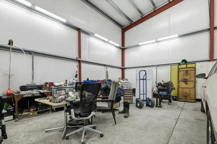 Spacious interior with exposed steel beams, high ceilings, concrete flooring, and ample linear lighting