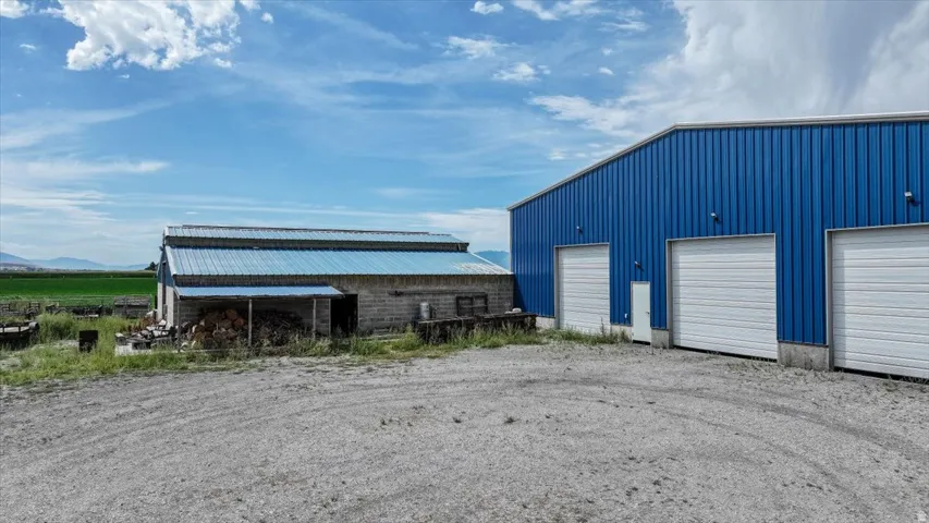 Blue metal-sided commercial building featuring three roll-up doors and a pedestrian door