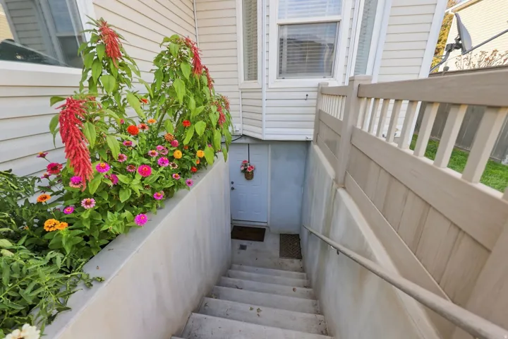 Concrete staircase with a metal handrail, leading to a white entry door