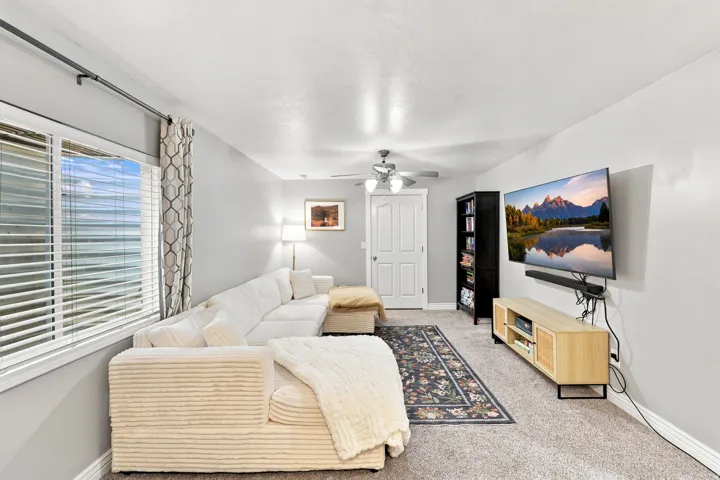 Recessed lighting, ceiling fan, white paneled door, large window with blinds, and wall-mounted television