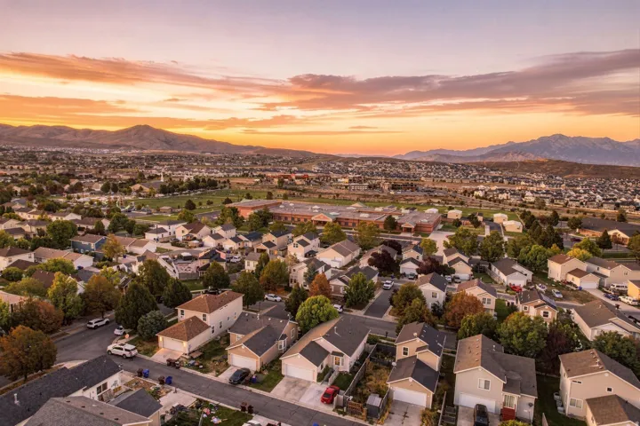 Residential neighborhood with varied architectural styles and mature trees, surrounded by distant mountains