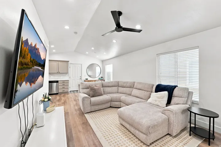 Vaulted ceiling with recessed lighting, wood-finish flooring, kitchen cabinetry, and a black ceiling fan