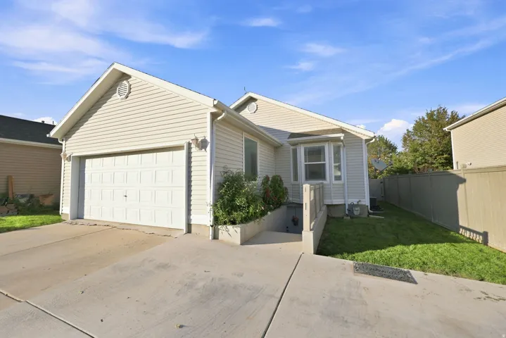 Exterior featuring light-colored siding, an attached garage, a concrete driveway, a bay window, and a fenced yard