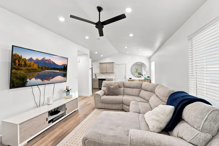 Vaulted ceiling with recessed lighting, wood-finish flooring, ceiling fan, and window with blinds