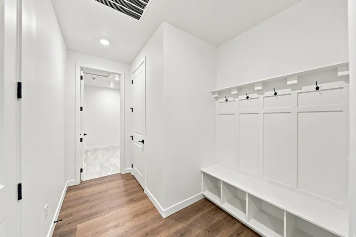Built-in mudroom bench with storage, wood-finish flooring, recessed lighting, and matte black hardware