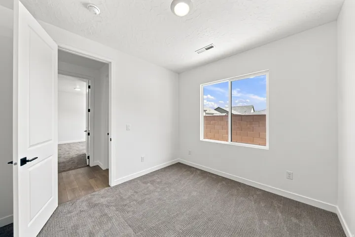 White interior walls, gray textured carpeting, and a window with a white frame