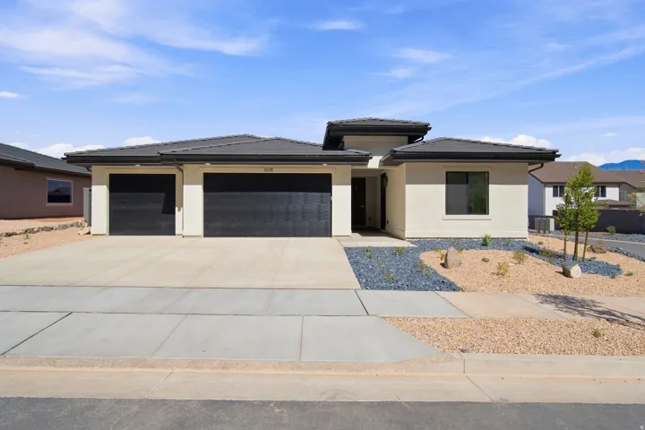 ** All photos are of a similar model**Contemporary stucco exterior with a tiled roof, a two-car garage, and desert-style landscaping