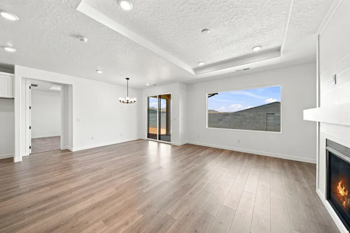 Wood-finish flooring, recessed lighting, tray ceiling, built-in fireplace, and sliding glass door