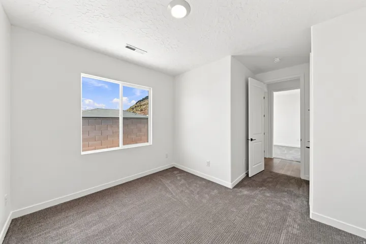 Room featuring light neutral wall paint, carpet flooring, a white window frame, and white trim