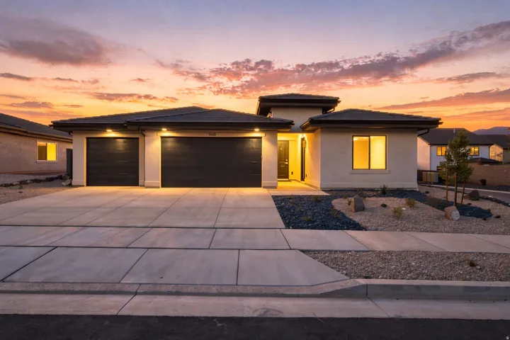 Contemporary stucco exterior with a multi-paneled garage door, concrete driveway, and desert-inspired landscaping