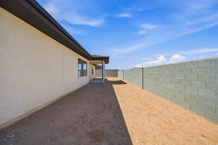 Stucco exterior with a covered patio, featuring a concrete block perimeter wall