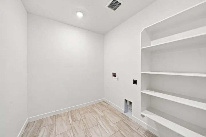 Utility space featuring tiled flooring, built-in shelving, white walls, and overhead lighting