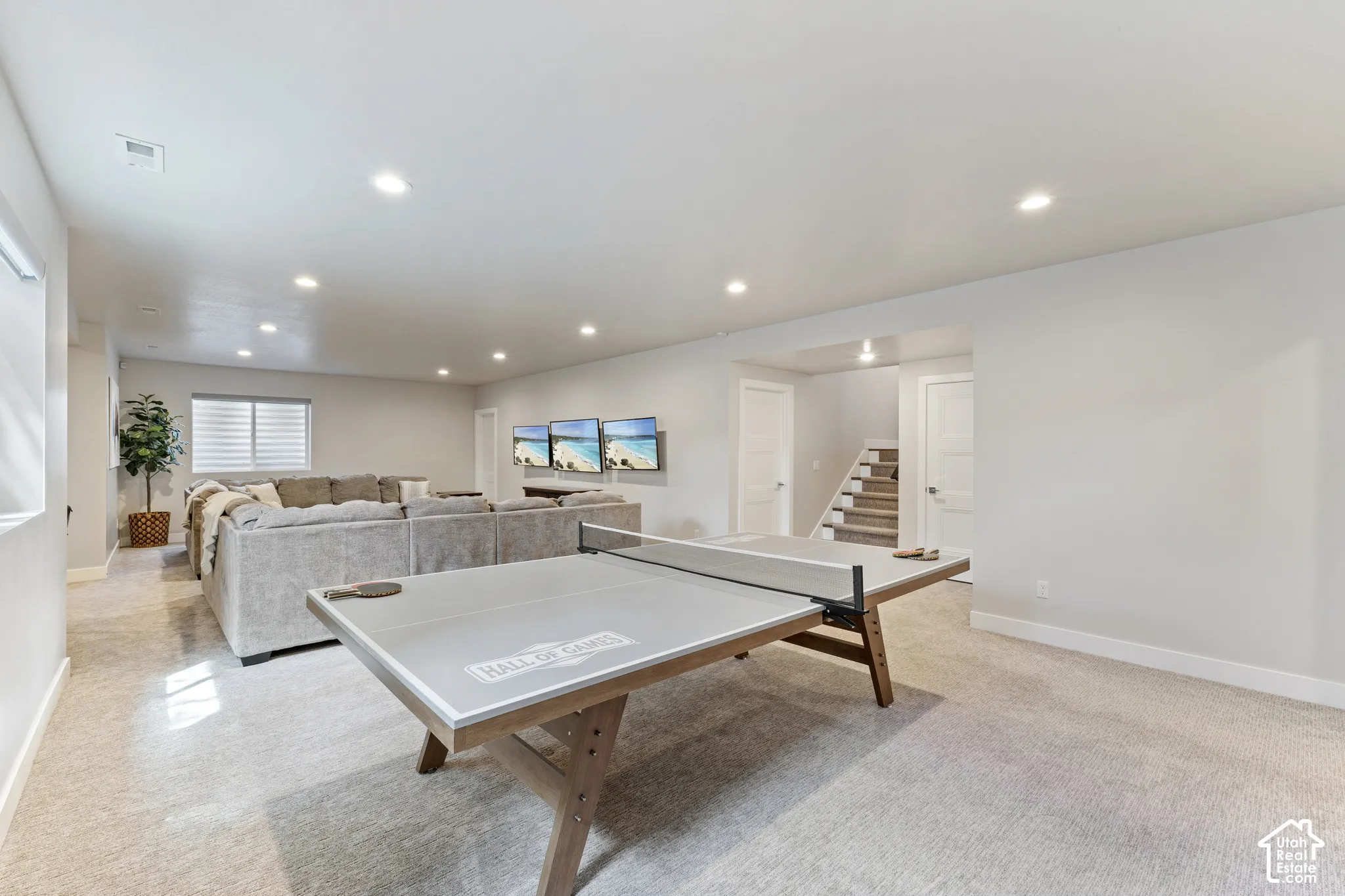 Expansive recreation room featuring engineered wood-finish flooring, recessed ceiling lighting, and a built-in ping pong table with wood base