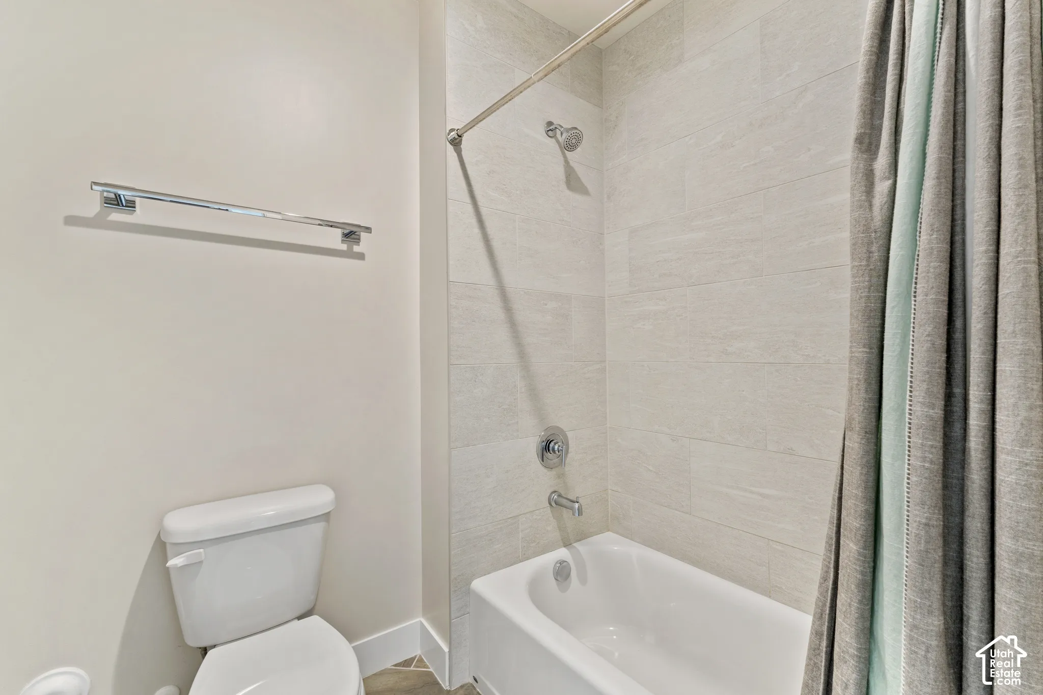 Clean and functional bathroom featuring a white porcelain toilet, alcove bathtub with tile surround, chrome showerhead and trim, and a fabric shower curtain