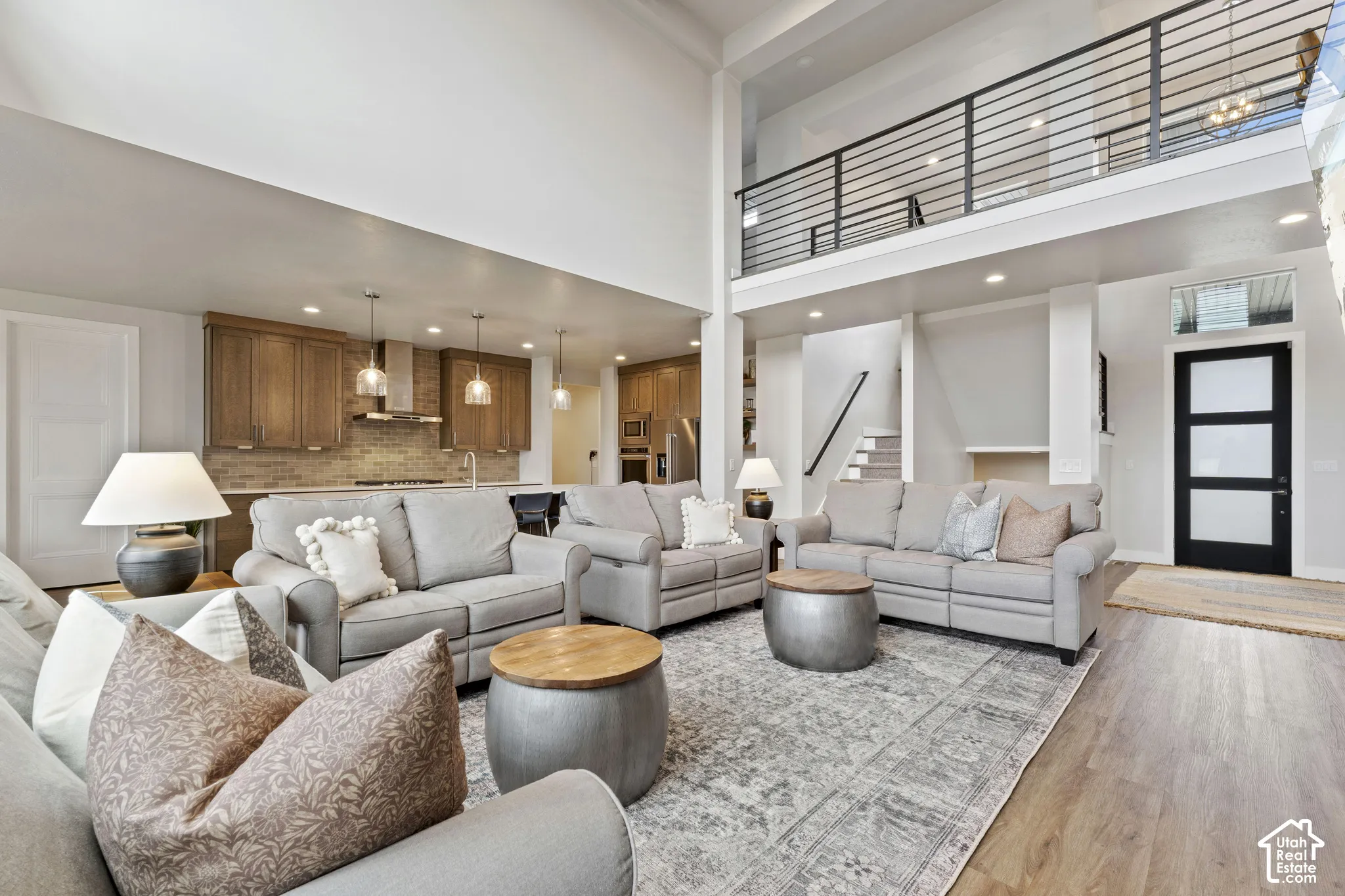 Open-concept living area featuring a two-story ceiling with clerestory windows, recessed lighting, and a mezzanine-level loft space