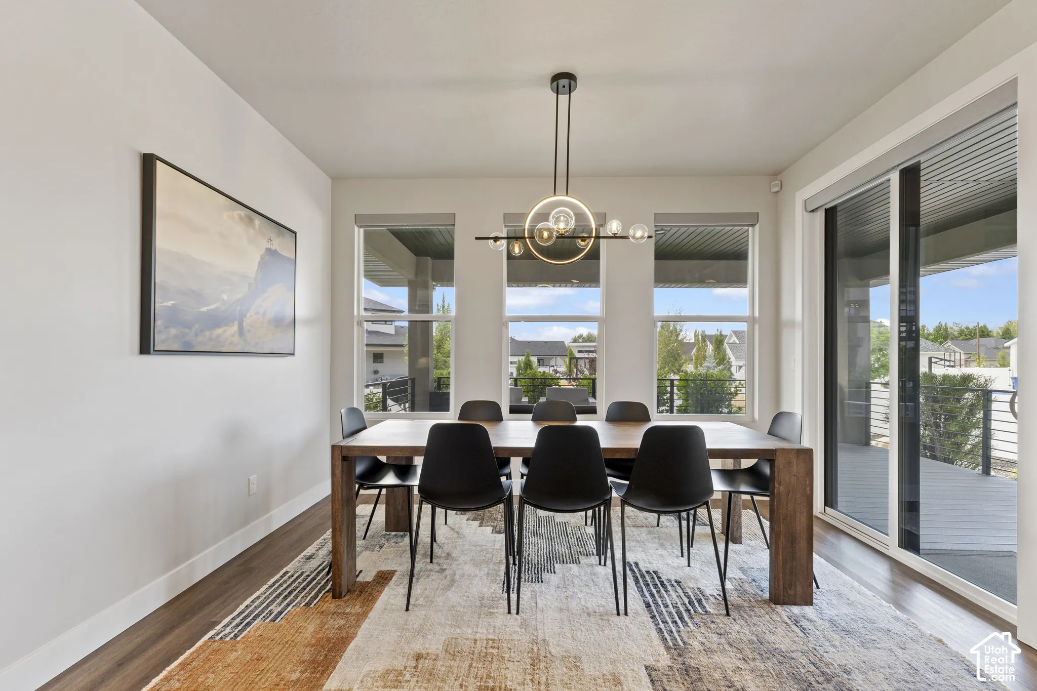 Sophisticated dining room featuring a wood-finish table with seating for six, wide-plank hardwood flooring, and a geometric area rug