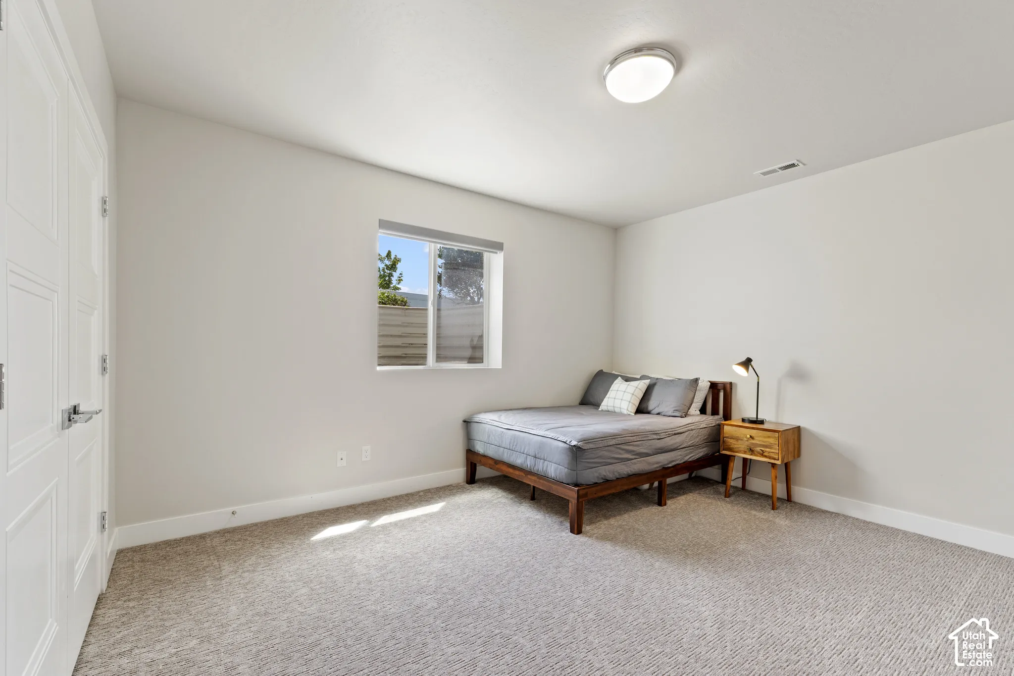 Bright secondary bedroom with neutral wall finishes, carpet flooring, and abundant natural light from a casement window
