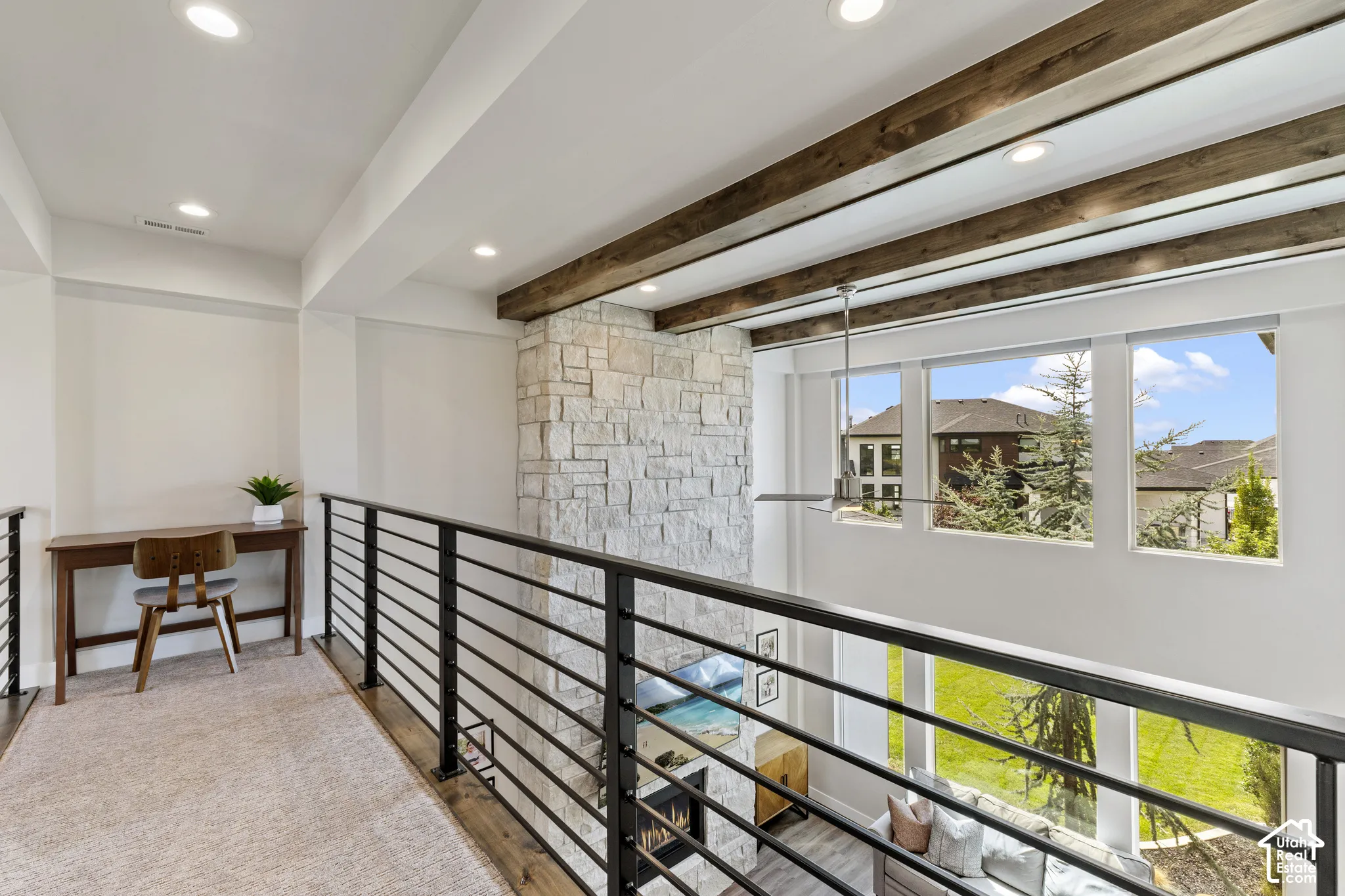 Modern loft-style mezzanine featuring exposed timber ceiling beams, recessed lighting, and horizontal metal railings