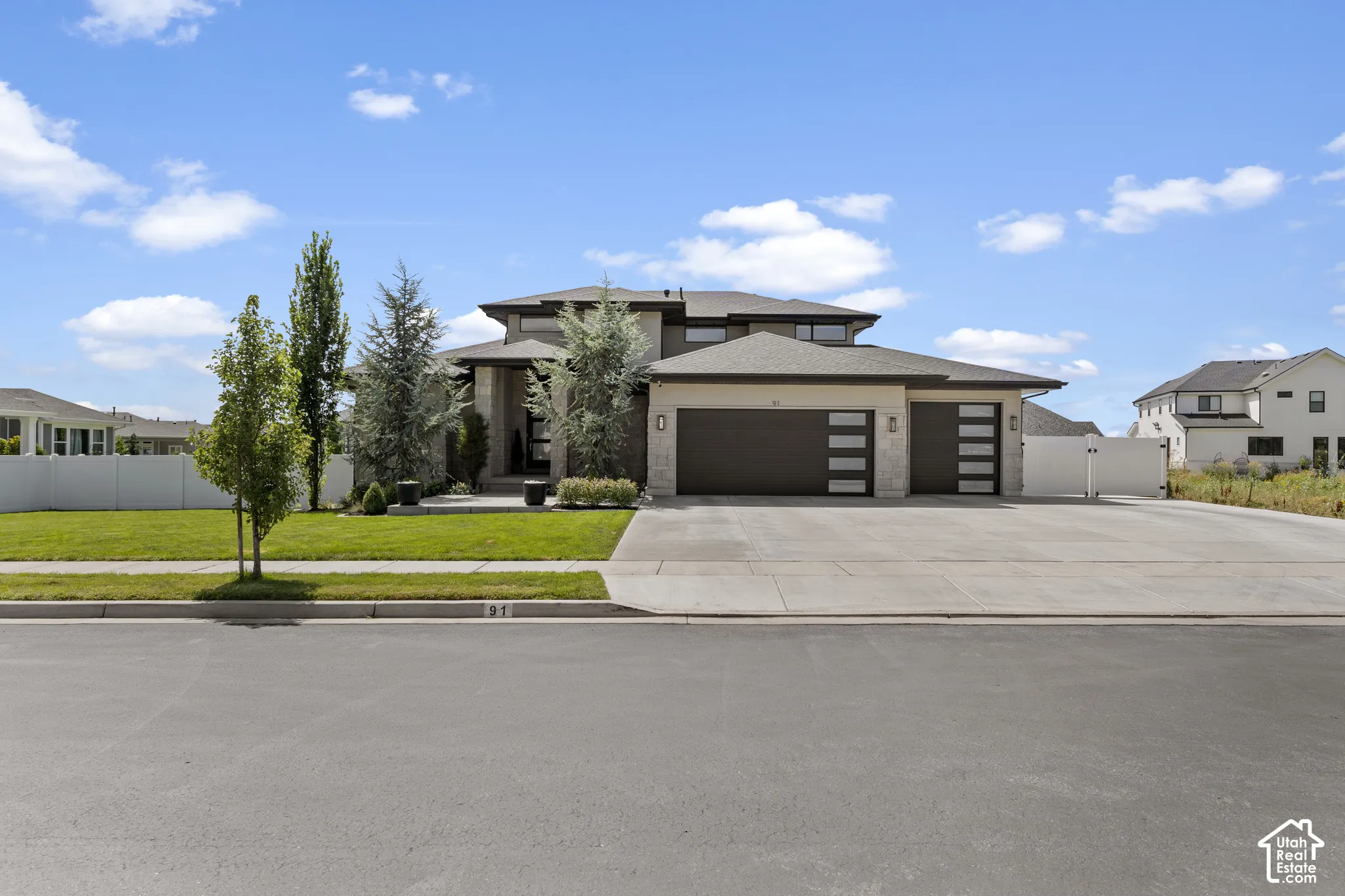 Contemporary two-story residence featuring a stepped roofline with clean architectural lines, dark horizontal garage doors, and a blend of earth-tone exterior finishes