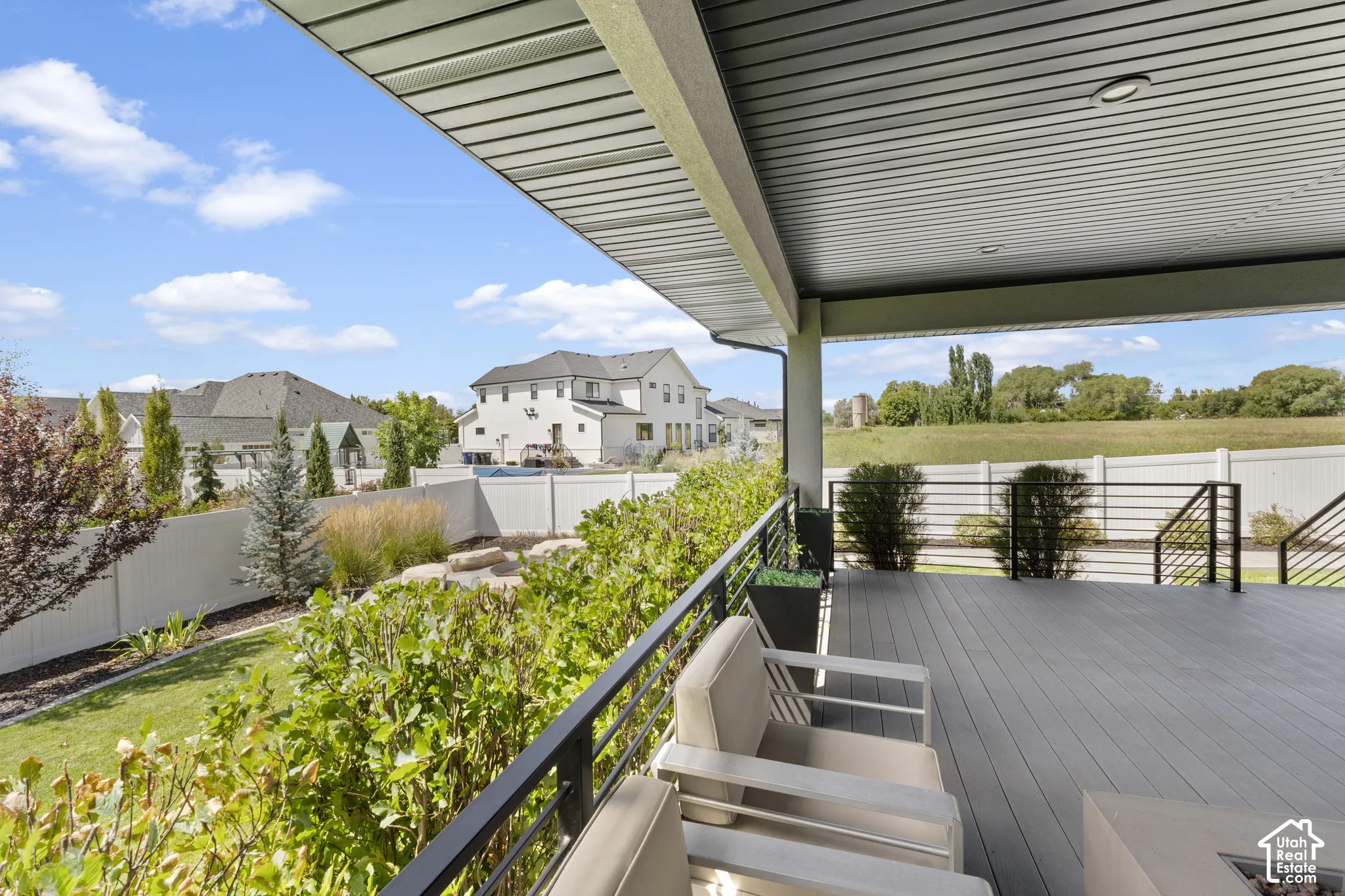 Expansive composite deck with composite decking and metal railings, sheltered by a modern pergola overhead