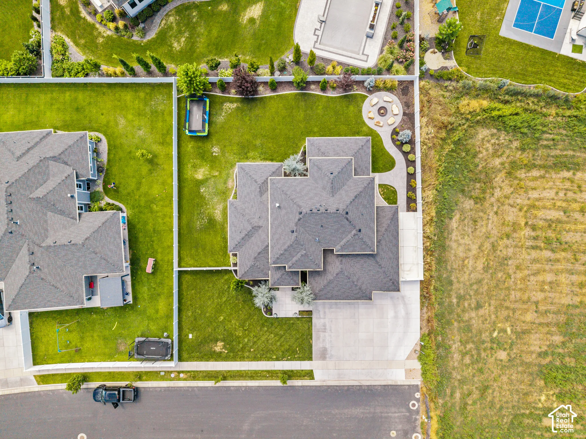 Aerial view showcasing a substantial two-story residence with a multi-peaked architectural design and gray composite roofing
