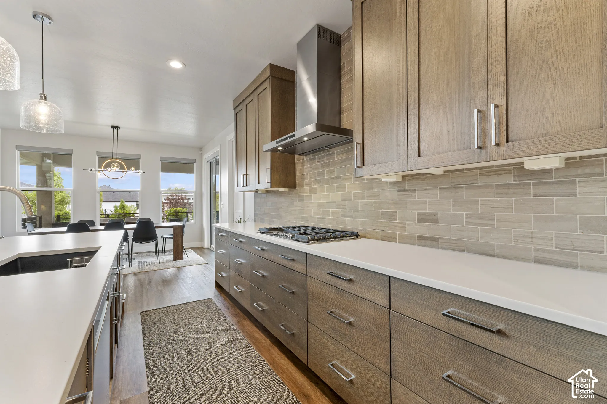 Contemporary kitchen featuring wood-finish cabinetry, white countertops, a tiled backsplash, and stainless steel appliances