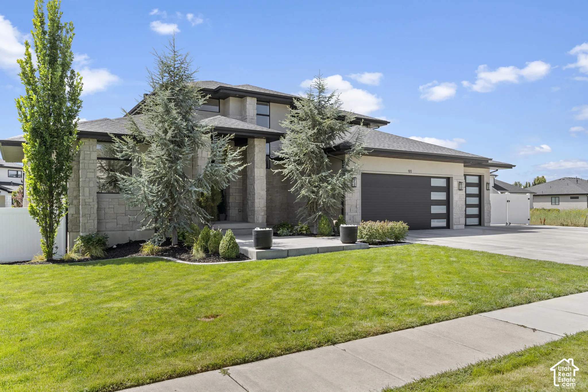 Modern two-story residence featuring a composite or stone exterior, multi-pane windows, and a contemporary flat-roofed design