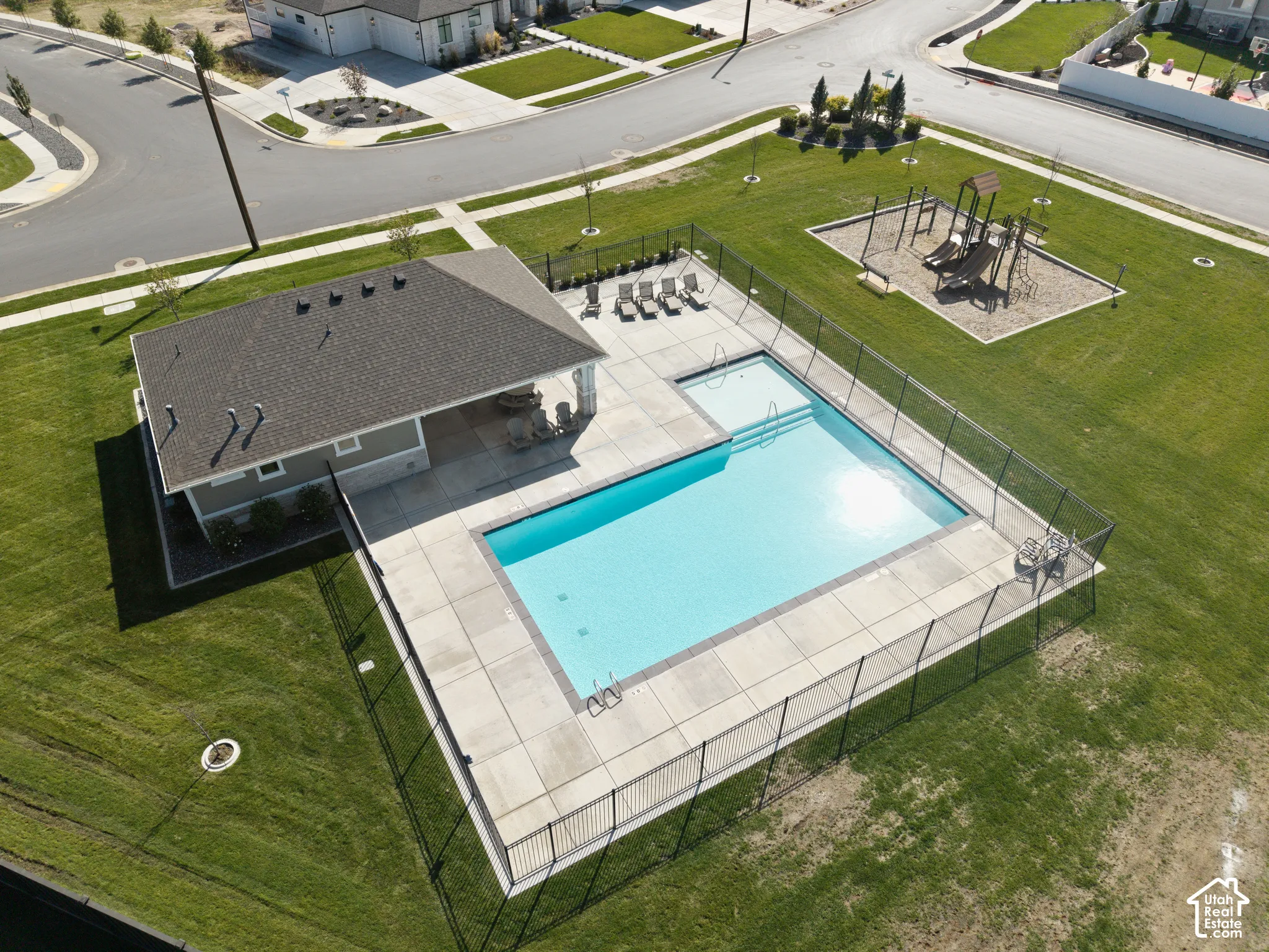 Community swimming pool with an integrated spa, surrounding concrete decking, and a covered patio structure