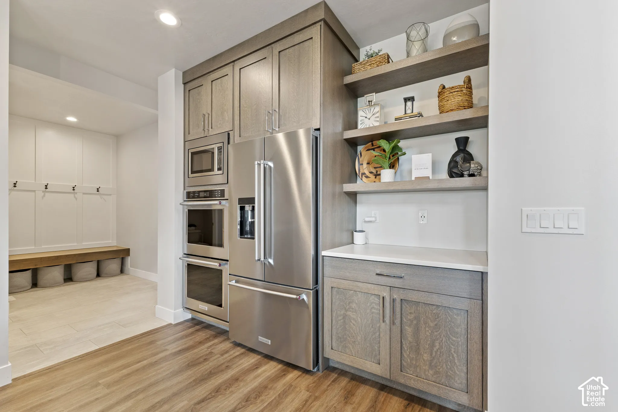 Modern kitchen featuring stainless steel French-door refrigerator, dual wall-mounted ovens, and built-in microwave