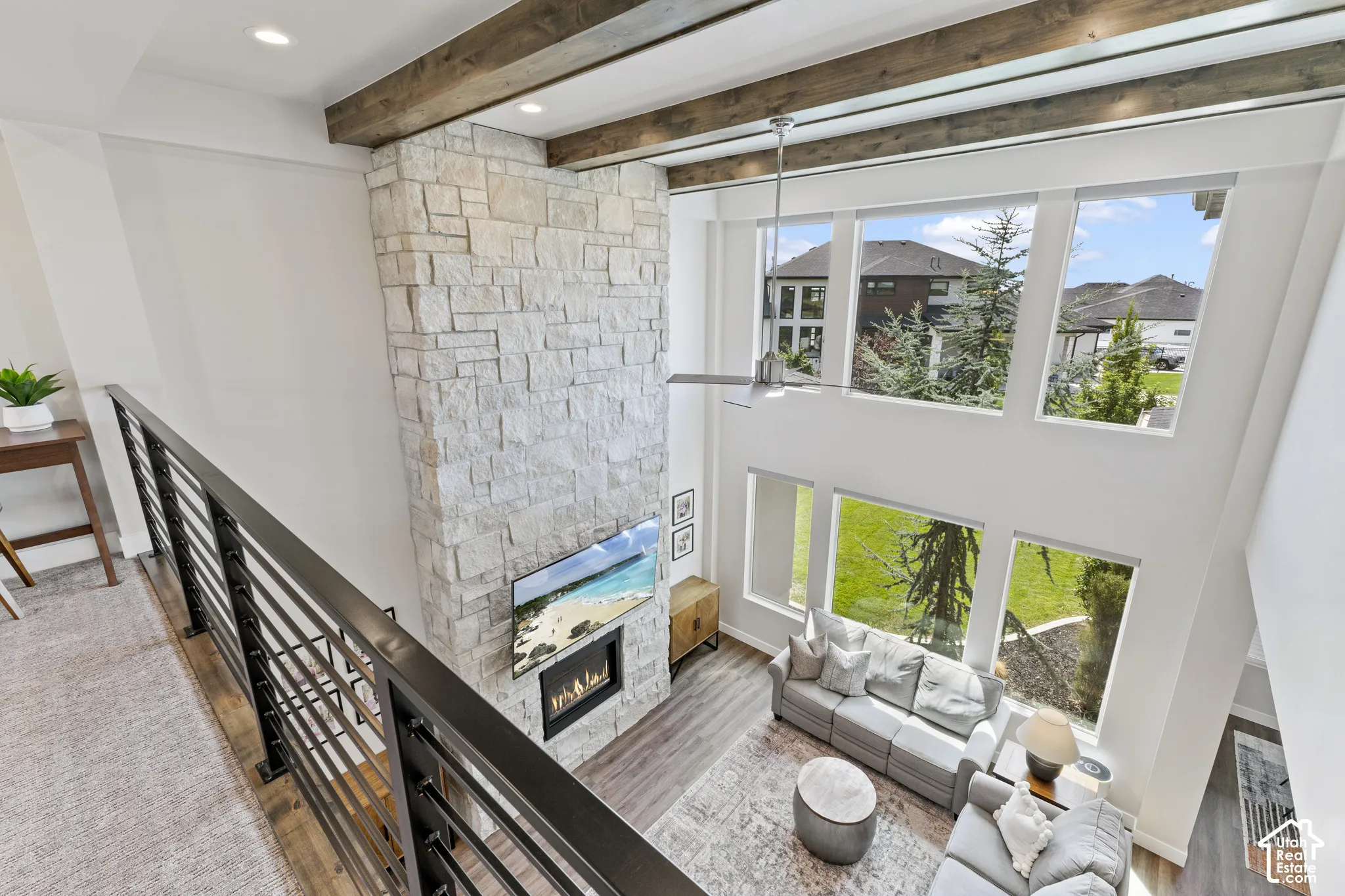 Two-story open-concept living area with soaring ceilings, exposed wooden beams, and abundant natural light from expansive multi-pane windows