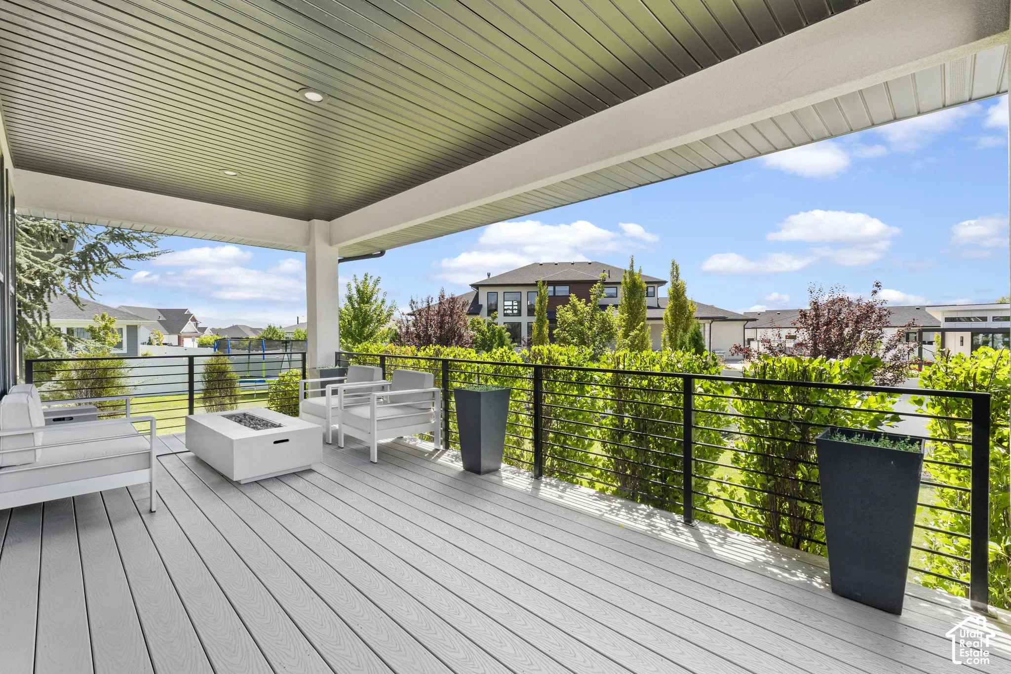Expansive composite deck with wood-finish flooring and a covered pavilion featuring a corrugated metal ceiling