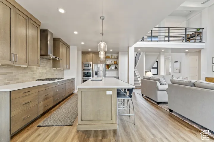 Open-concept living space with wood-finish flooring, a kitchen island, and a second-level balcony