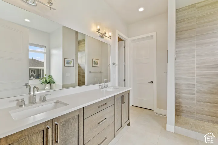 Spa-inspired primary bathroom showcasing a lengthy dual-sink vanity with wood-finish cabinetry, white quartz countertops, and polished nickel fixtures