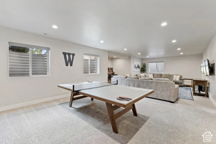 Spacious carpeted room featuring recessed lighting, a wall-mounted television, and multiple windows