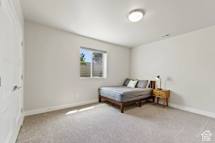 Bright secondary bedroom with neutral wall finishes, carpet flooring, and abundant natural light from a casement window
