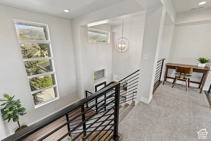 Modern upper-level landing featuring a black horizontal cable railing system, light wood-finish flooring, and abundant natural light from a multi-pane window