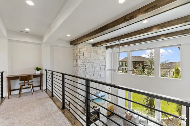 Modern loft-style mezzanine featuring exposed timber ceiling beams, recessed lighting, and horizontal metal railings