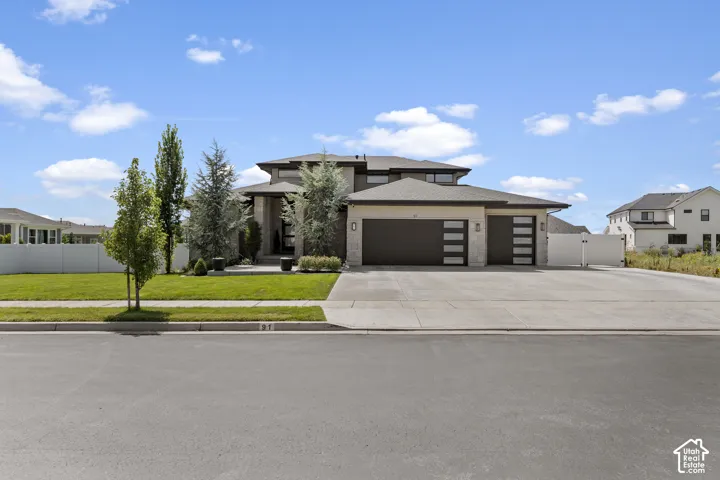 Contemporary two-story residence featuring a stepped roofline with clean architectural lines, dark horizontal garage doors, and a blend of earth-tone exterior finishes