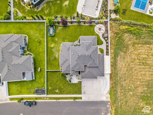 Aerial view showcasing a substantial two-story residence with a multi-peaked architectural design and gray composite roofing