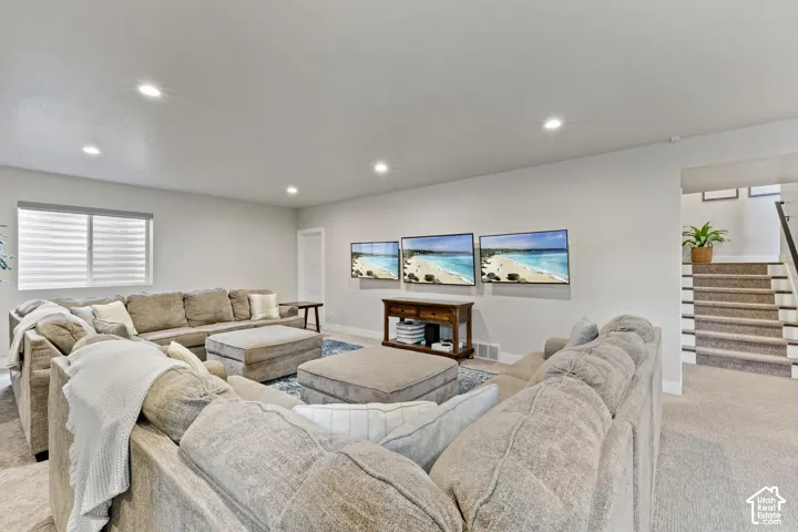 Expansive rec room featuring recessed ceiling lighting, neutral wall finishes, and multiple seating areas anchored by a wood-finish media console